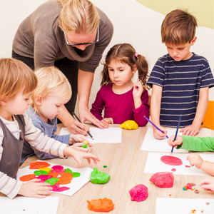 Des enfants qui dessine avec l'aide d'une adulte, promotion d'une formation continue.