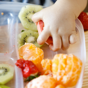 Plusieurs fruits et un enfant qui les prend à la main, promotion d'une formation continue.