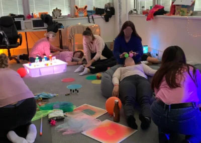 Formation Snoezelen : les participants réalisent des massages sensoriels à l'aide d'objets du quotidien dans une salle décorée