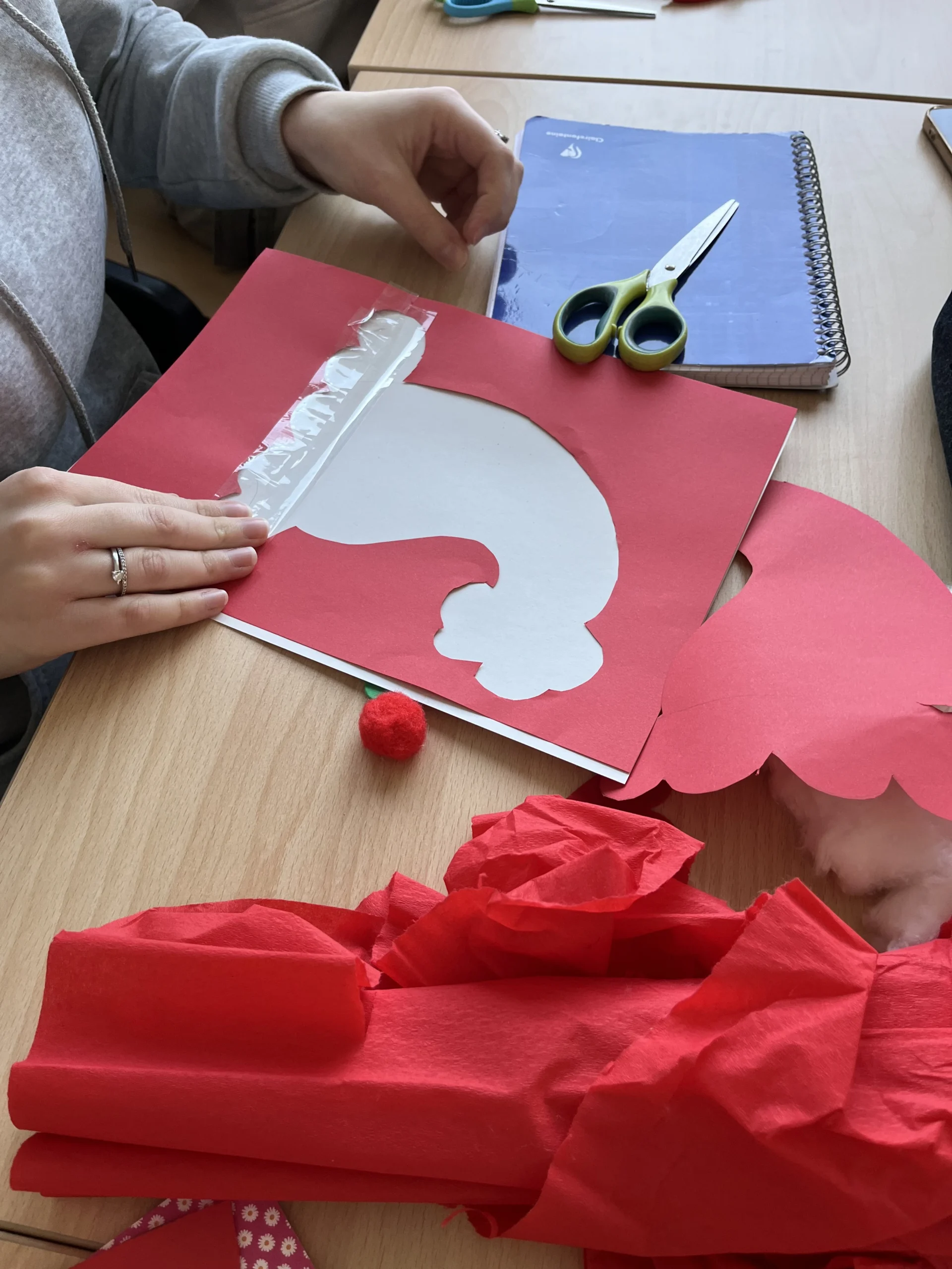 Activité manuelle de Noël : une apprentie applique le ruban adhésif sur son dessin de bonnet de Noël