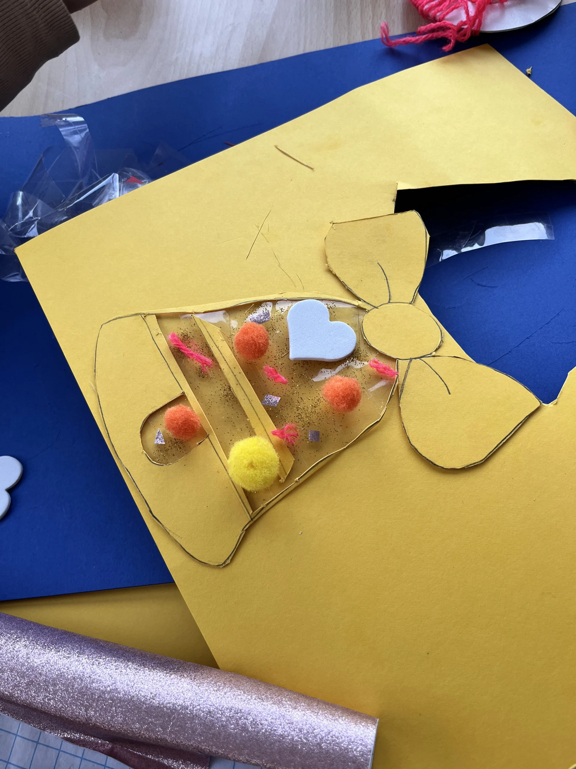 Un bricolage en forme de cloche décoré avec des pompons