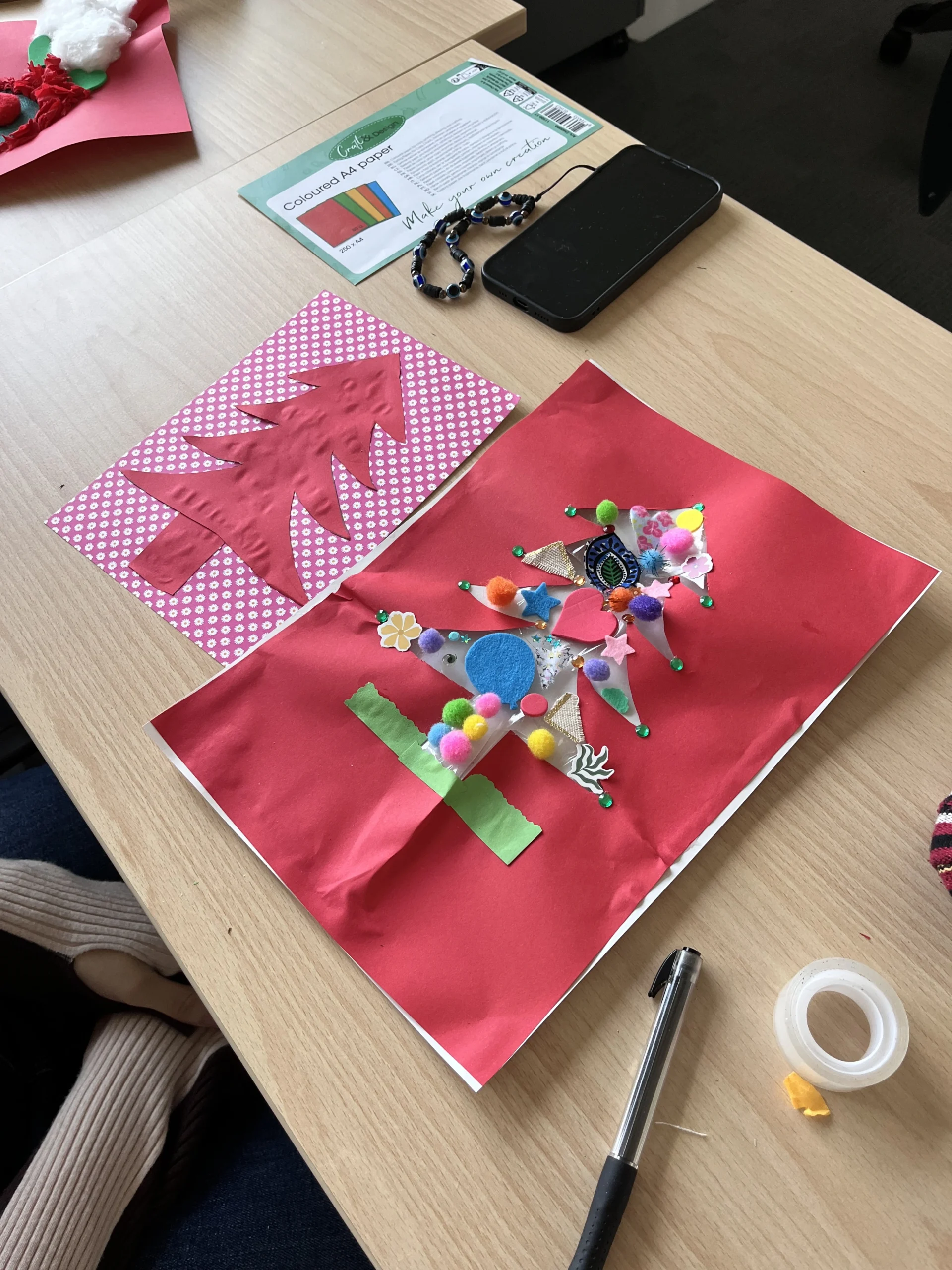 Un dessin de sapin finalisé, décoré avec des pompons et des stickers