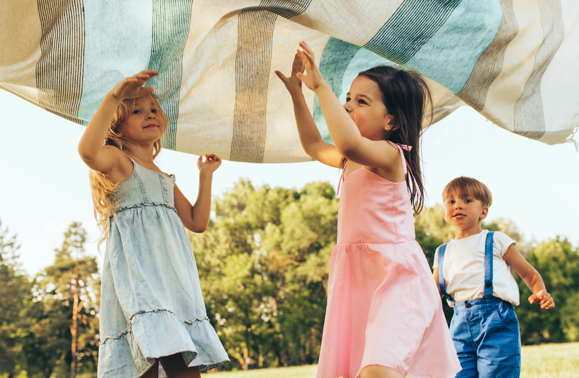 Activités danse et éveil corporel jeune enfant : des enfants jouent sous un drap à l'extérieur