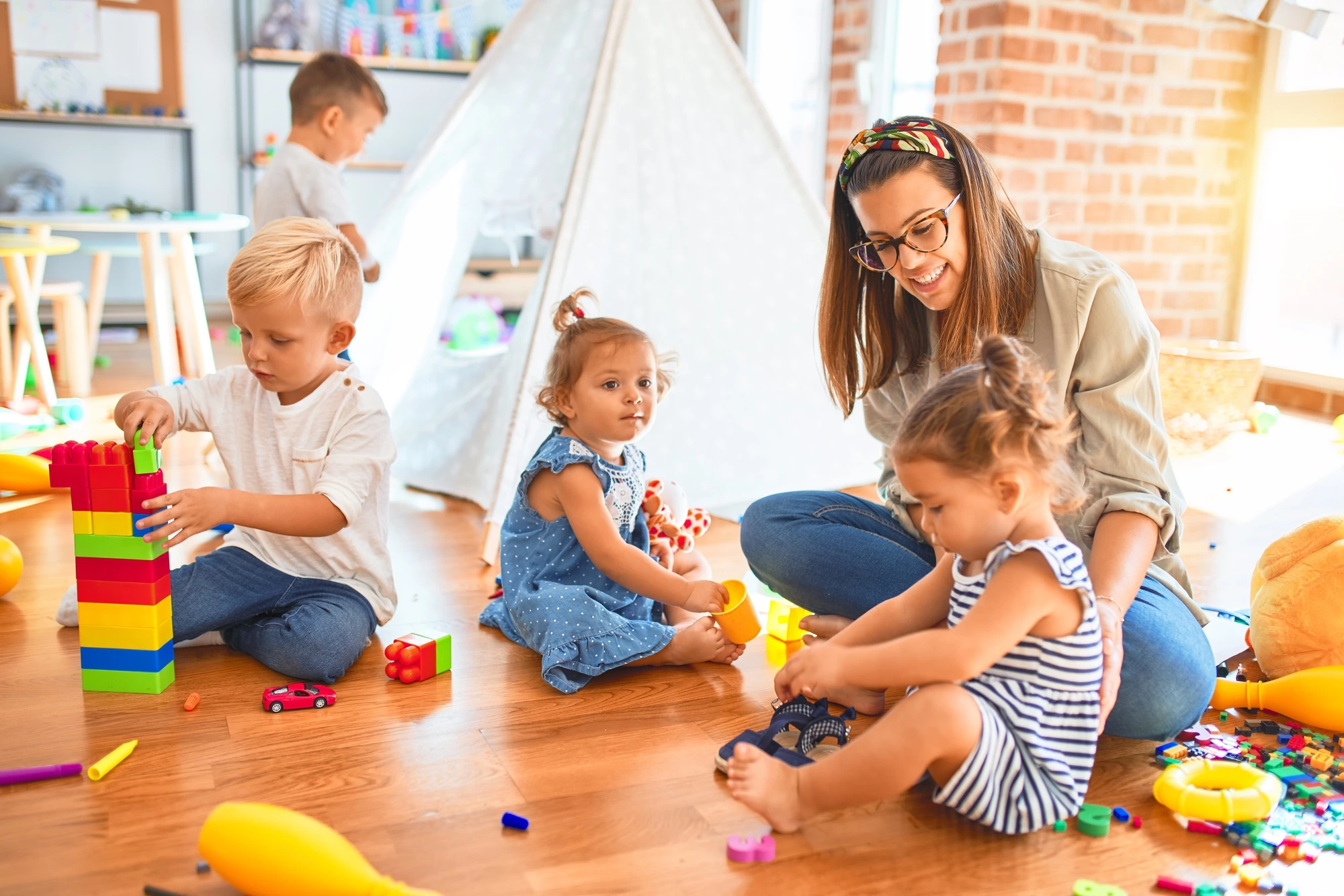 Formations Petite Enfance Strasbourg 2026 : une jeune femme s'occupe de quatres enfants en jouant avec eux dans une crèche